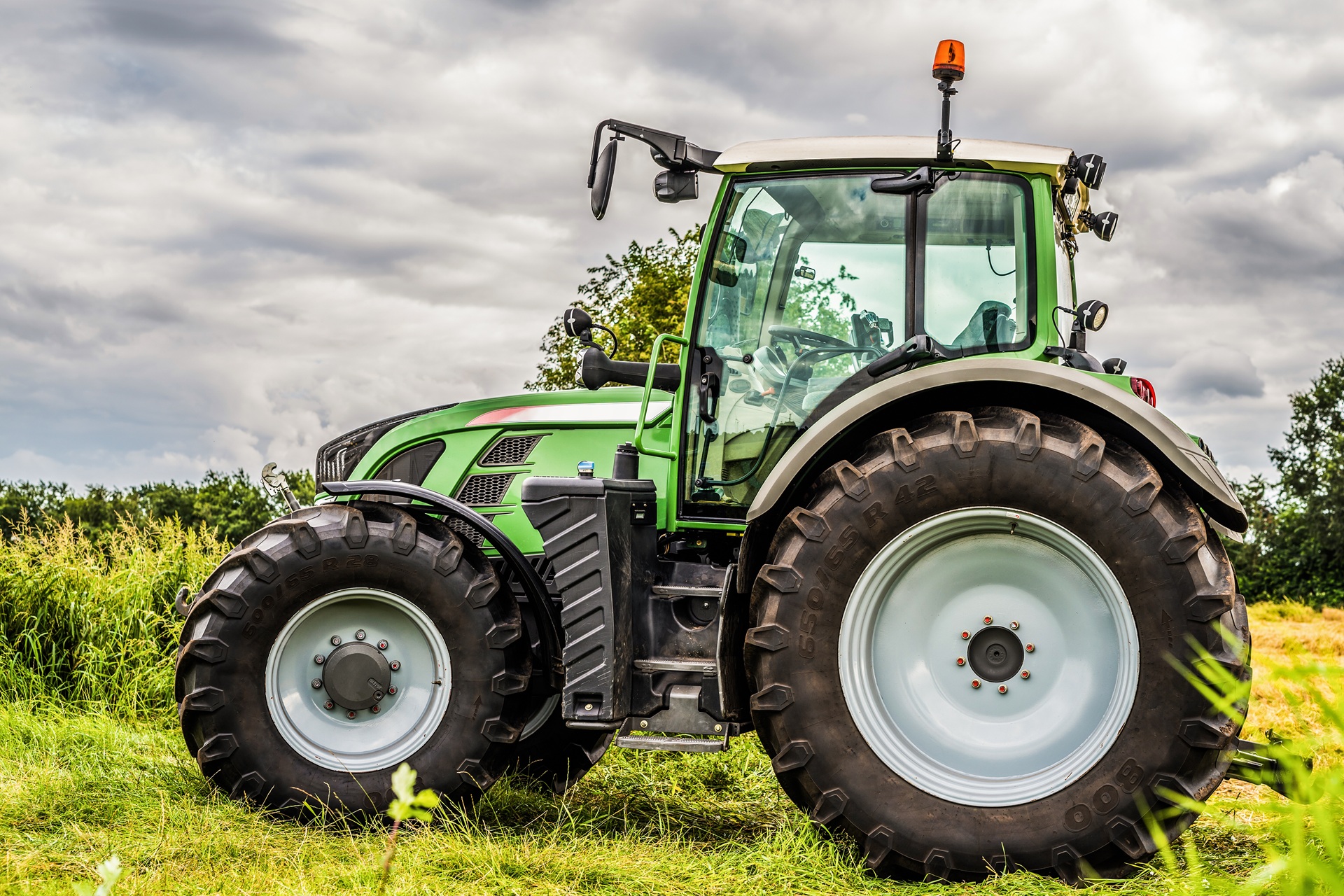 Grüner Traktor auf Wiese im Einsatz | hydraulischer Oberlenker
